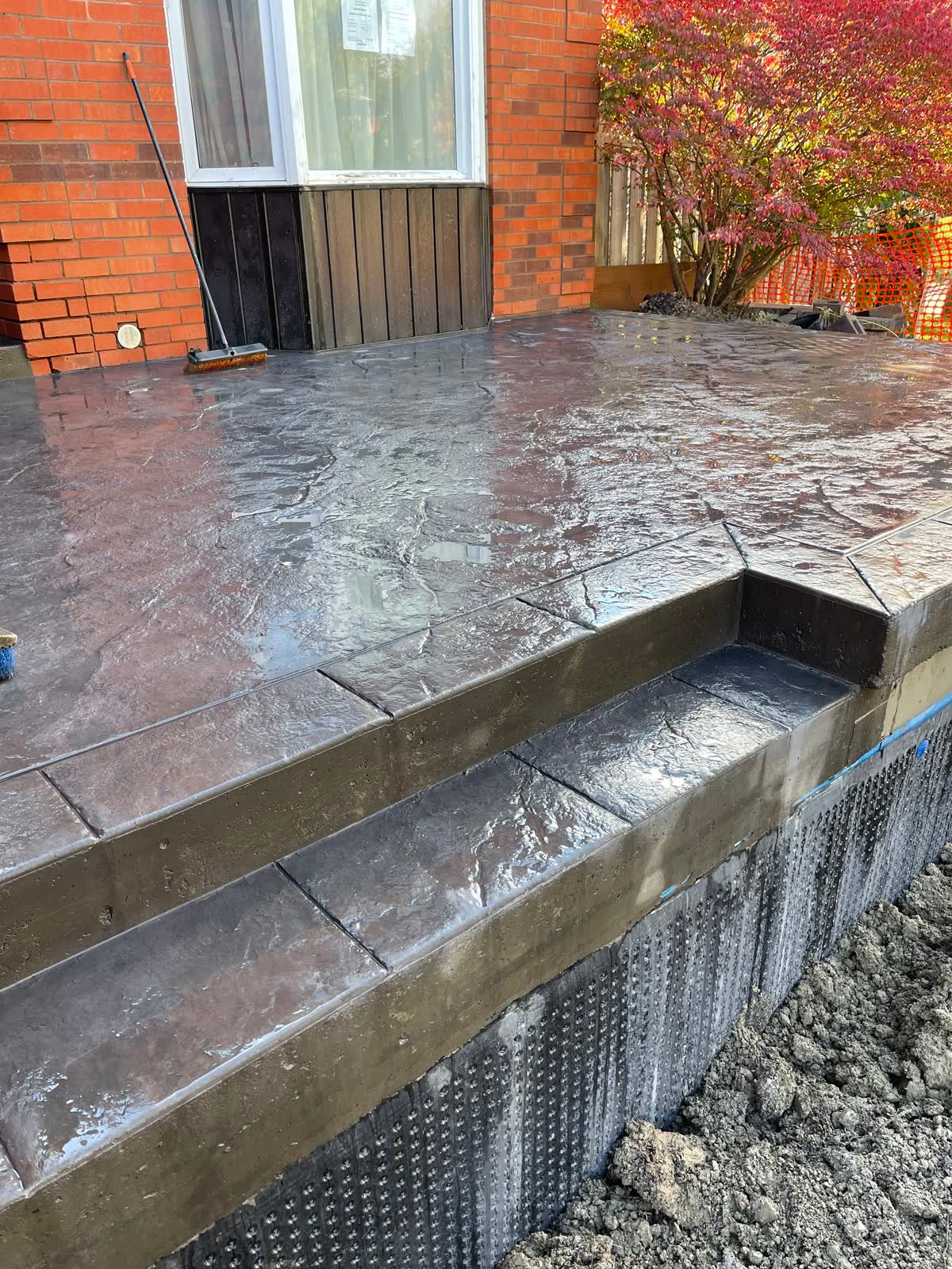 Slate-textured stamped concrete porch and steps against a brick house, coloured and sealed
