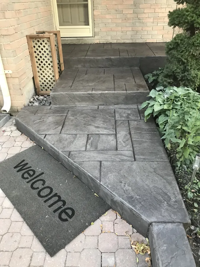 Charcoal ashlar-slate stamped concrete porch and steps beside a brick house