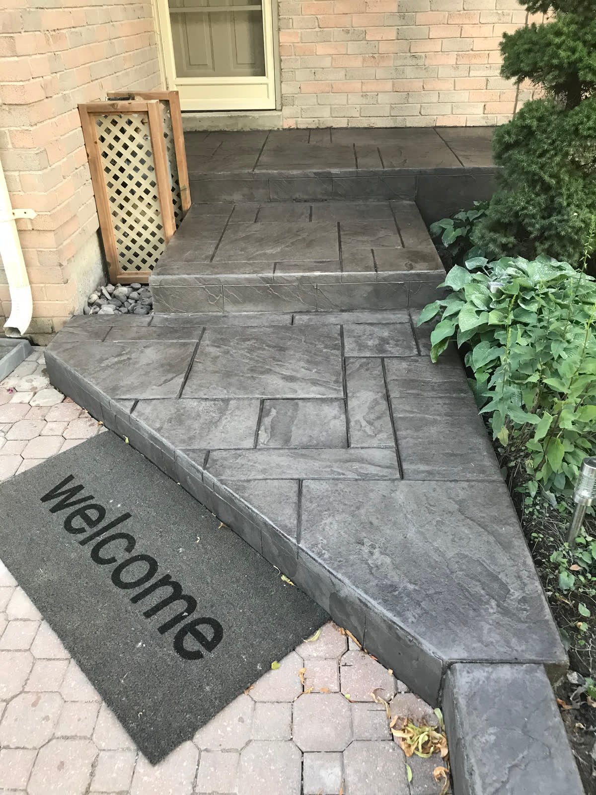 Charcoal ashlar-slate stamped concrete porch and steps beside a brick house