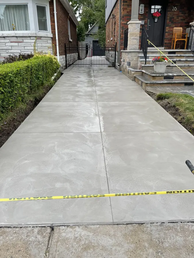 Long narrow smooth-finished concrete driveway running between two houses to a rear gate