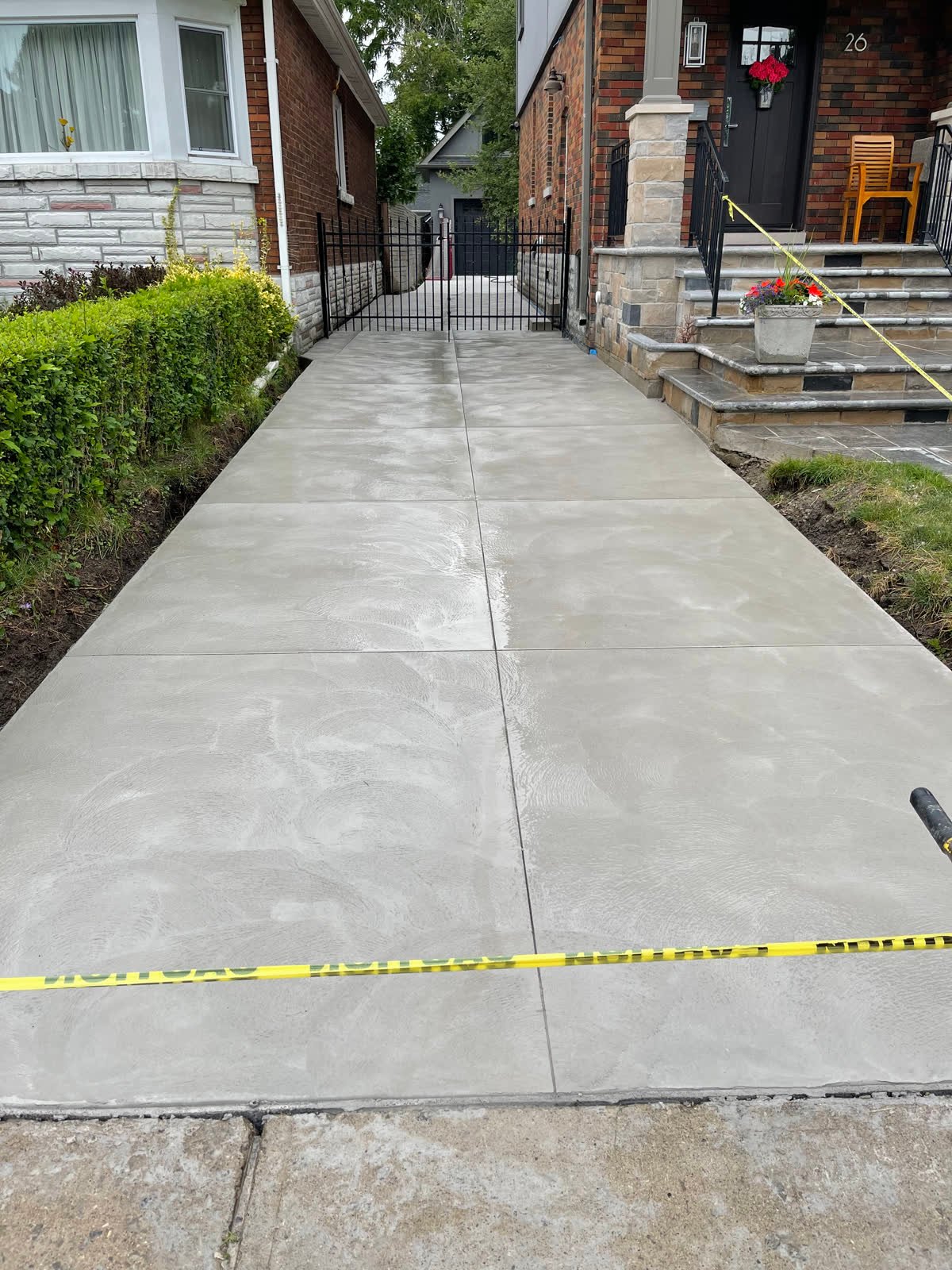 Long narrow smooth-finished concrete driveway running between two houses to a rear gate